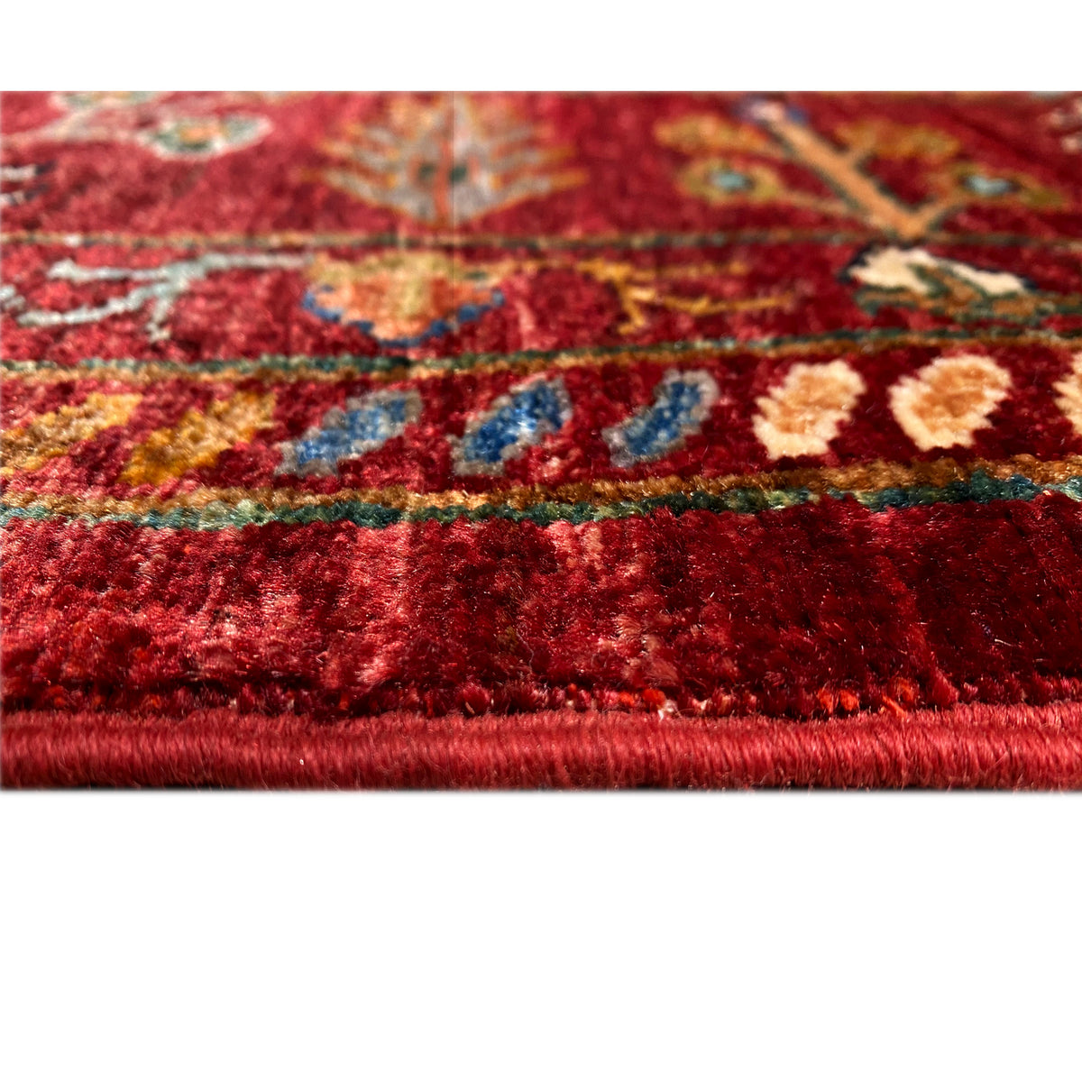 Detail of the carpet pile: red fabric with multicolored patterns and a visible edge