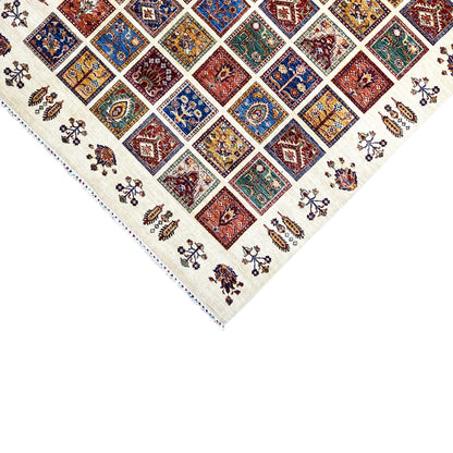 Wool rug edge detail: tile pattern and small floral ornaments on a cream-colored background