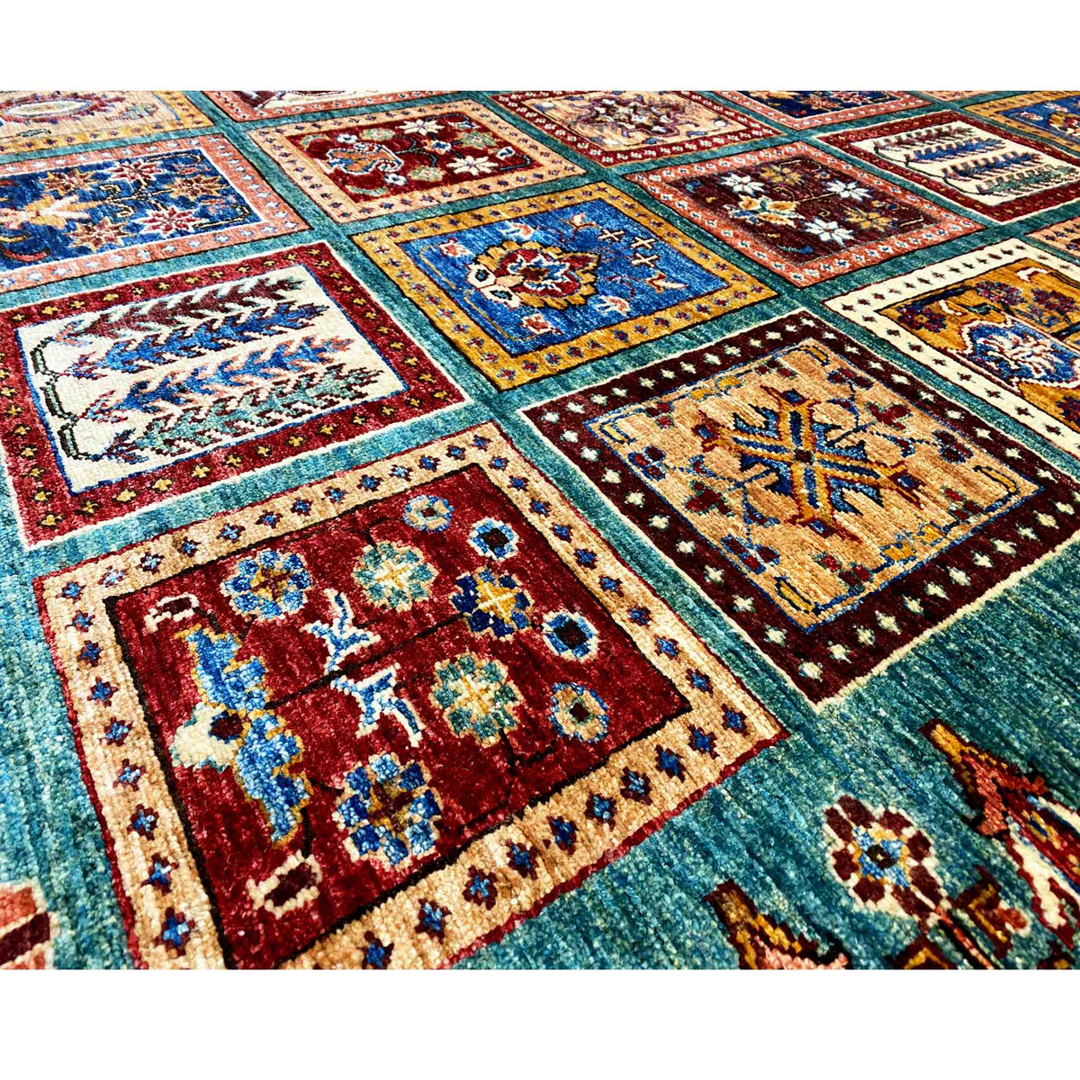 Ziegler carpet close-up with bold ornamental areas in blue, red, and beige on petrol blue