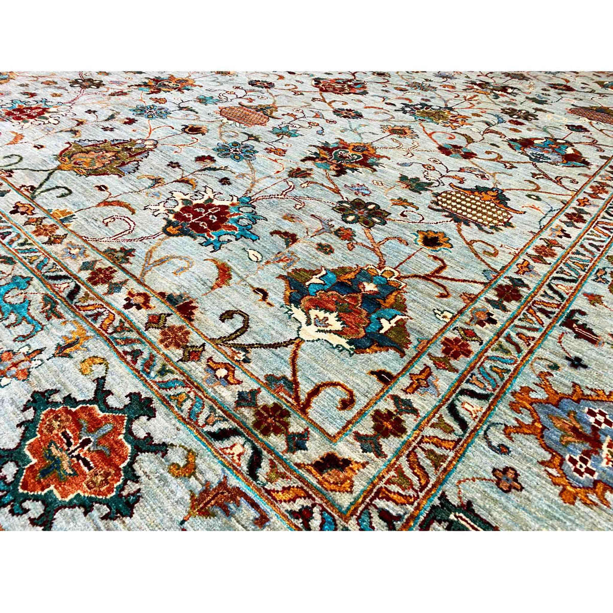 Close-up of a carpet surface with a delicate ornamental and floral pattern in light blue