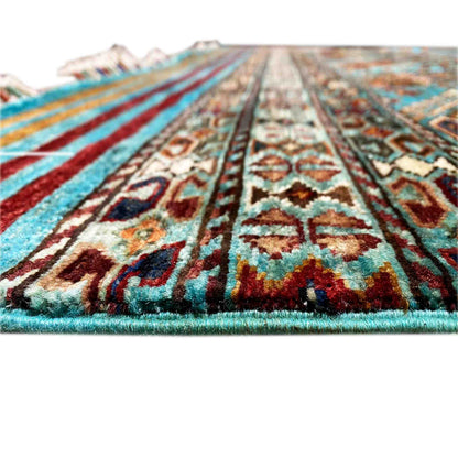 Close-up of a carpet: dense ornaments, turquoise-blue and red accents, fringe