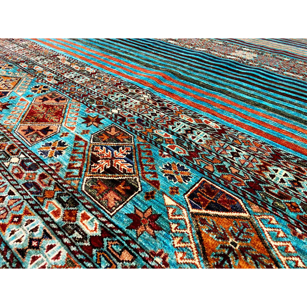 Close-up of a rug with an ornamental border and turquoise stripes, colorful details