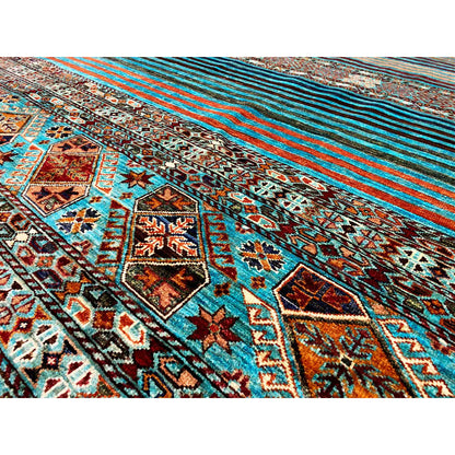 Close-up of a rug with an ornamental border and turquoise stripes, colorful details