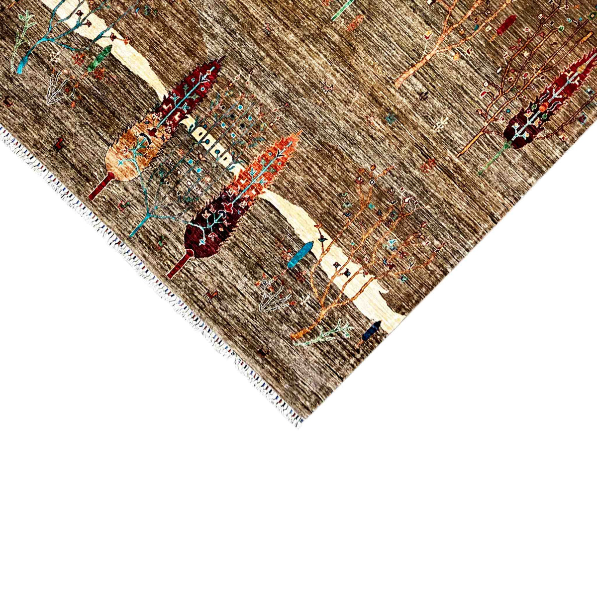 Close-up of the carpet corner: brown base, colorful ornaments, and fringes along the edge
