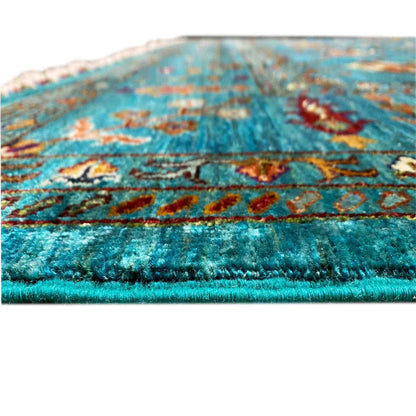Close-up: turquoise carpet pile with colorful patterns, fringed edge