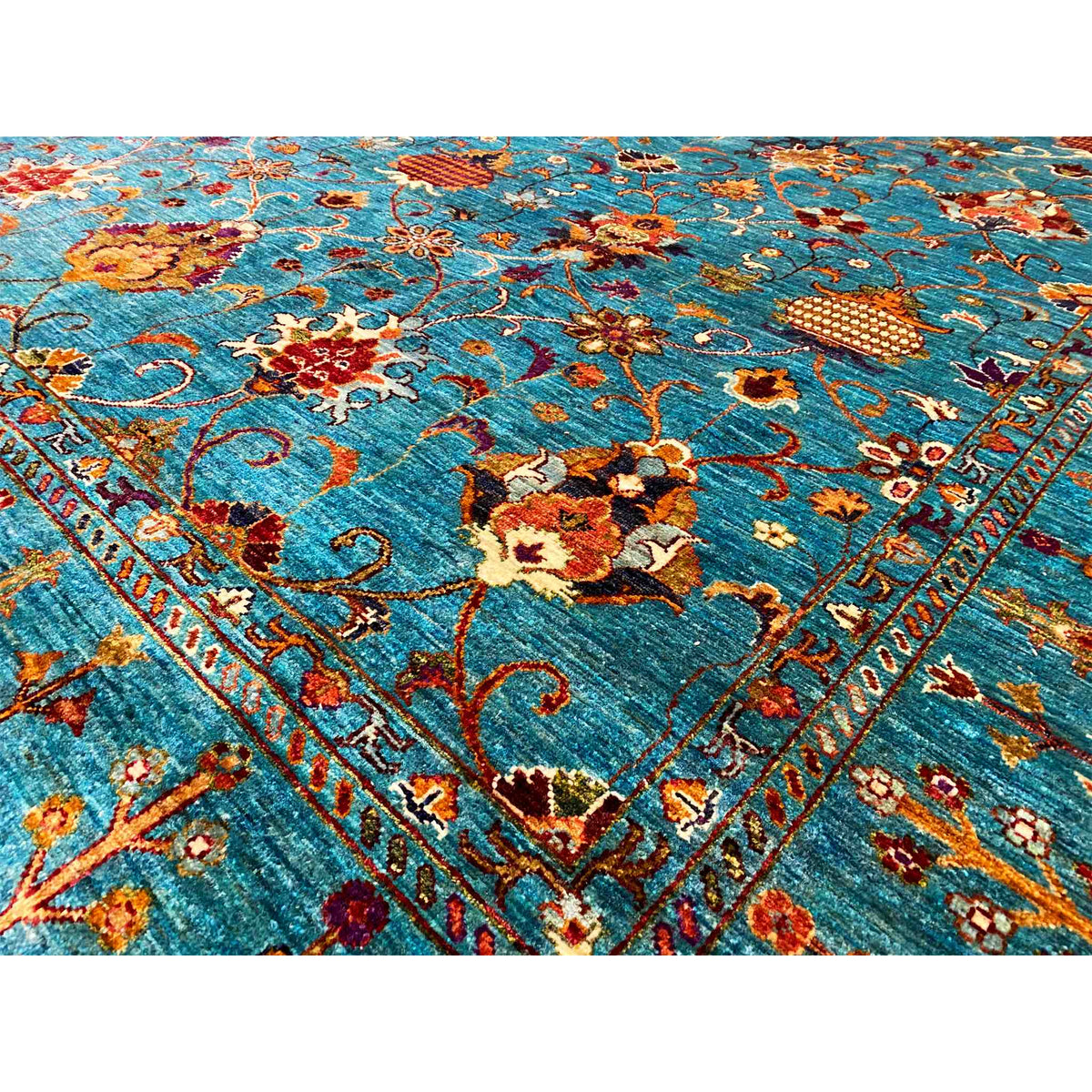 Close-up of carpet: dense floral and ornamental pattern in turquoise, red, and gold