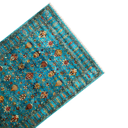 Turquoise rug with a colorful ornamental pattern, angled view and fringes