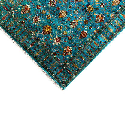 Corner close-up: turquoise rug with a colorful ornamental pattern, fringes along the edge