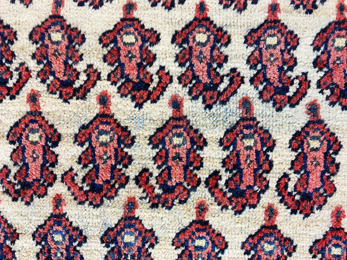 Close-up of carpet pattern: repeating medallions in red, dark blue, and cream
