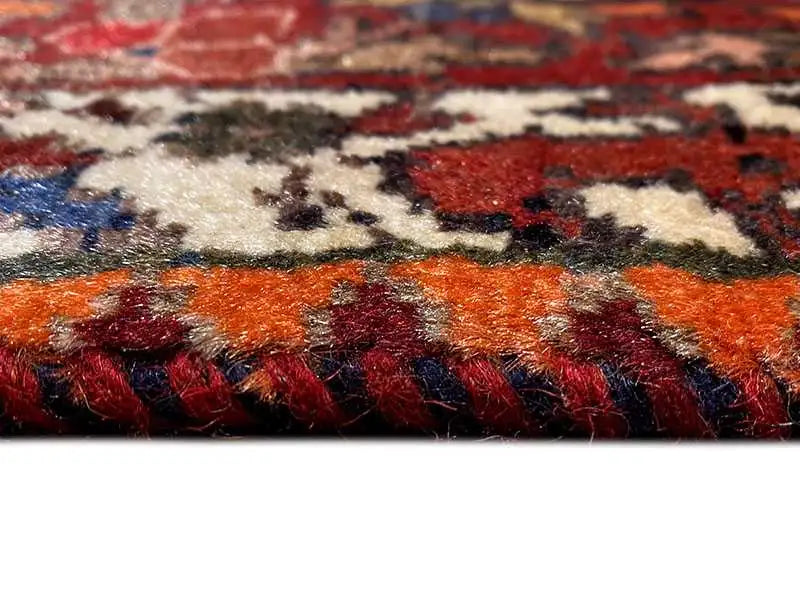 Close-up view of the carpet pile with colorful yarns in red, orange, blue, and beige