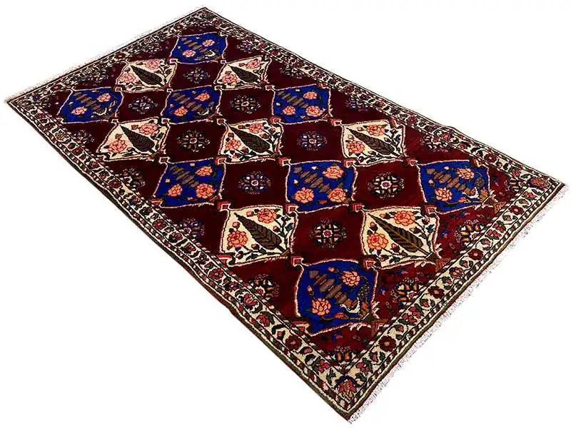 Bakhtiari rug laid flat: burgundy background with blue diamonds, cream-colored accents, border.