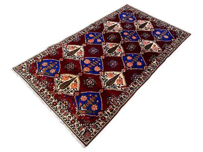 Flat Bakhtiari rug: burgundy, bold blue, and cream with geometric medallions in the pattern.