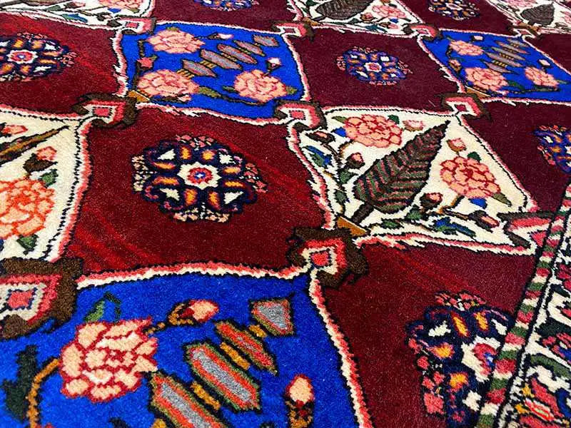 Bakhtiari rug detail: burgundy field with blue ornaments, floral motifs, and a fine border.