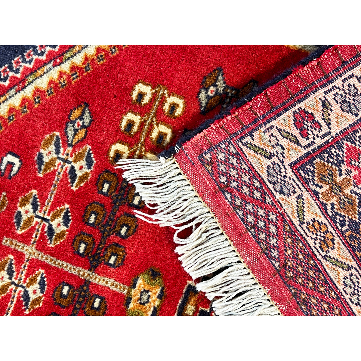 Baluch rug with a red geometric pattern and white fringes