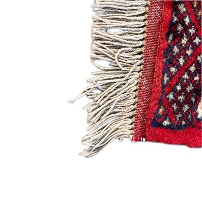 Baluch carpet edge with fringe and red border, visible dark patterned area