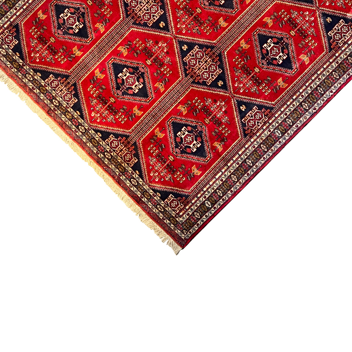 Baluchi rug corner in oblique view: red pattern, dark blue border, and bound edge