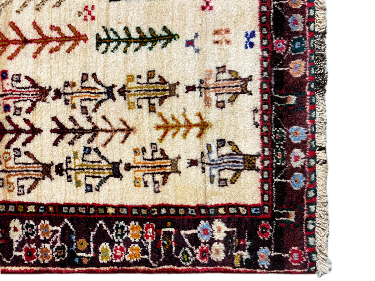 Baluch rug detail with conifer motifs and a dark border frieze, cream-colored base