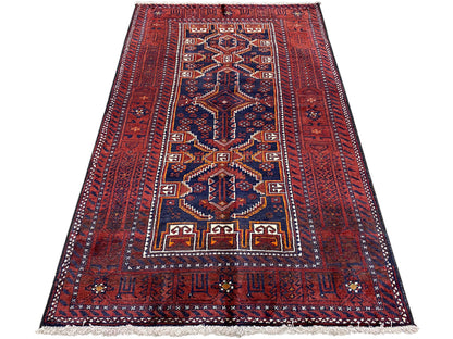 Rectangular Baluchi rug, red with blue and gold geometric designs, with fringes.