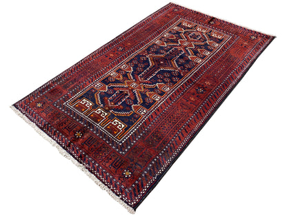 Rectangular Baluchi rug, red with a blue central motif, fine patterns, and fringes along the edges.