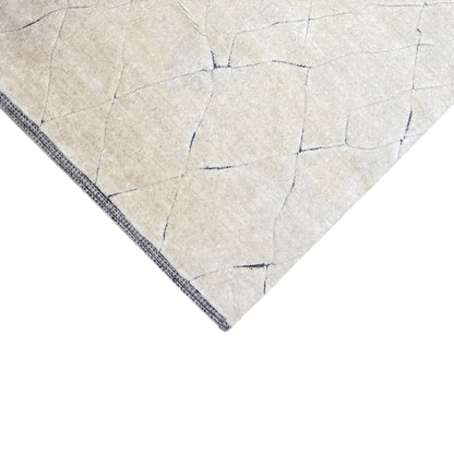 Corner view of the cream-colored rug with a blue border and geometric lines