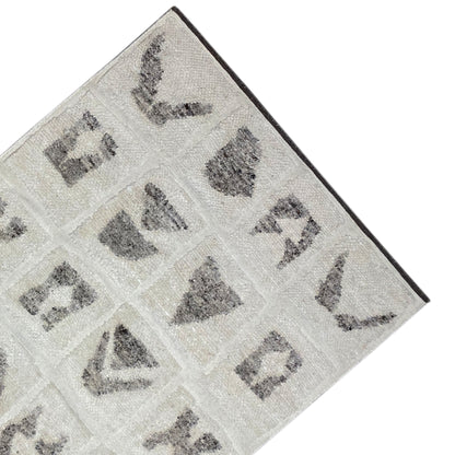 Detailed view of the edge: Berber rug with a beige background and gray motif panels