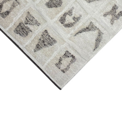 Corner of the Berber rug with a beige background, gray symbols, and a clean edge