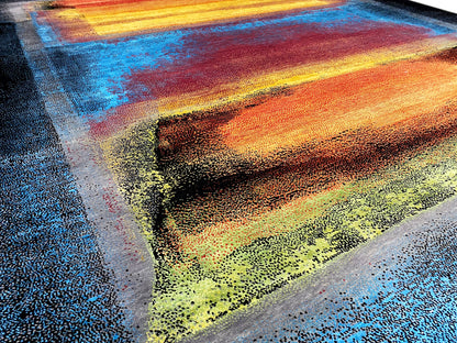 Close-up of the rug with an abstract banded pattern in blue, orange, yellow, and green