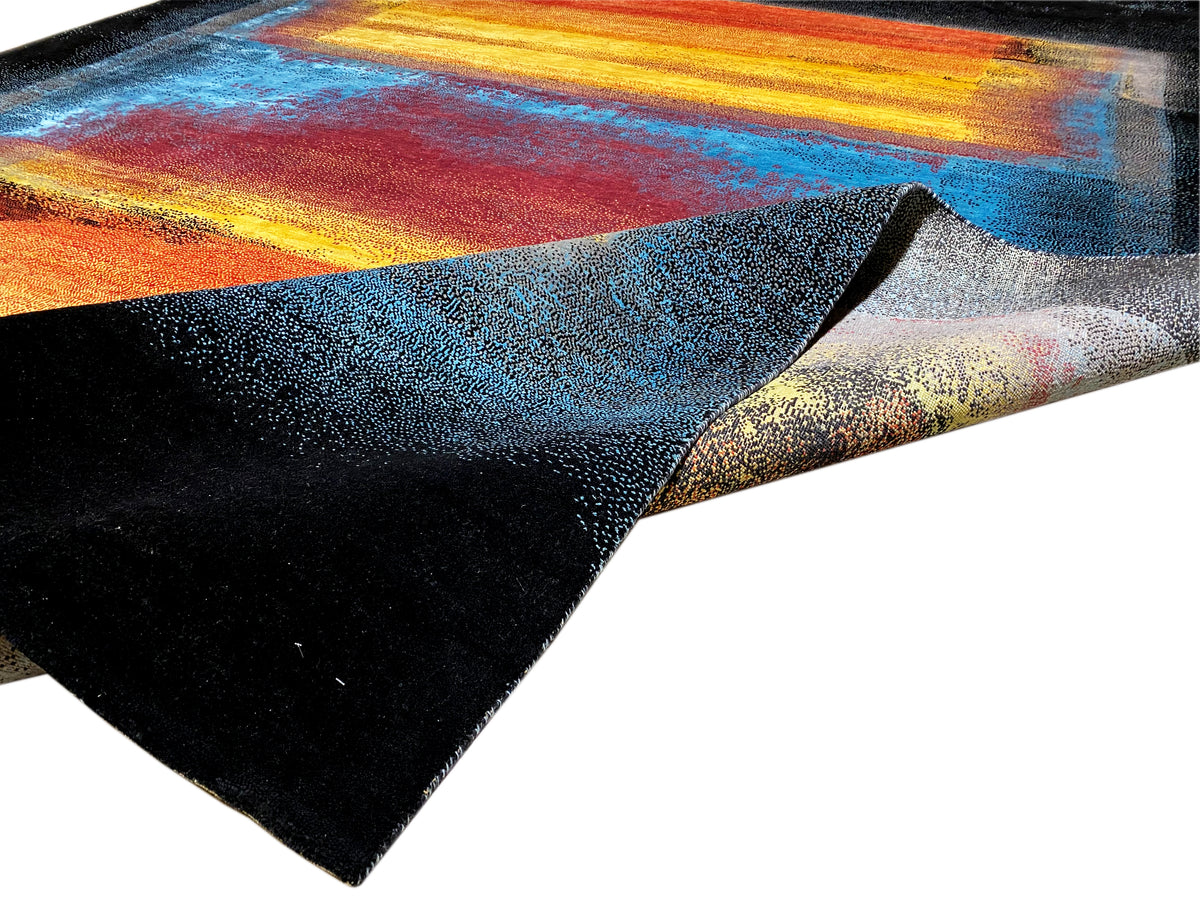 Rug at an angle with a dark border and colorful blue and orange sections