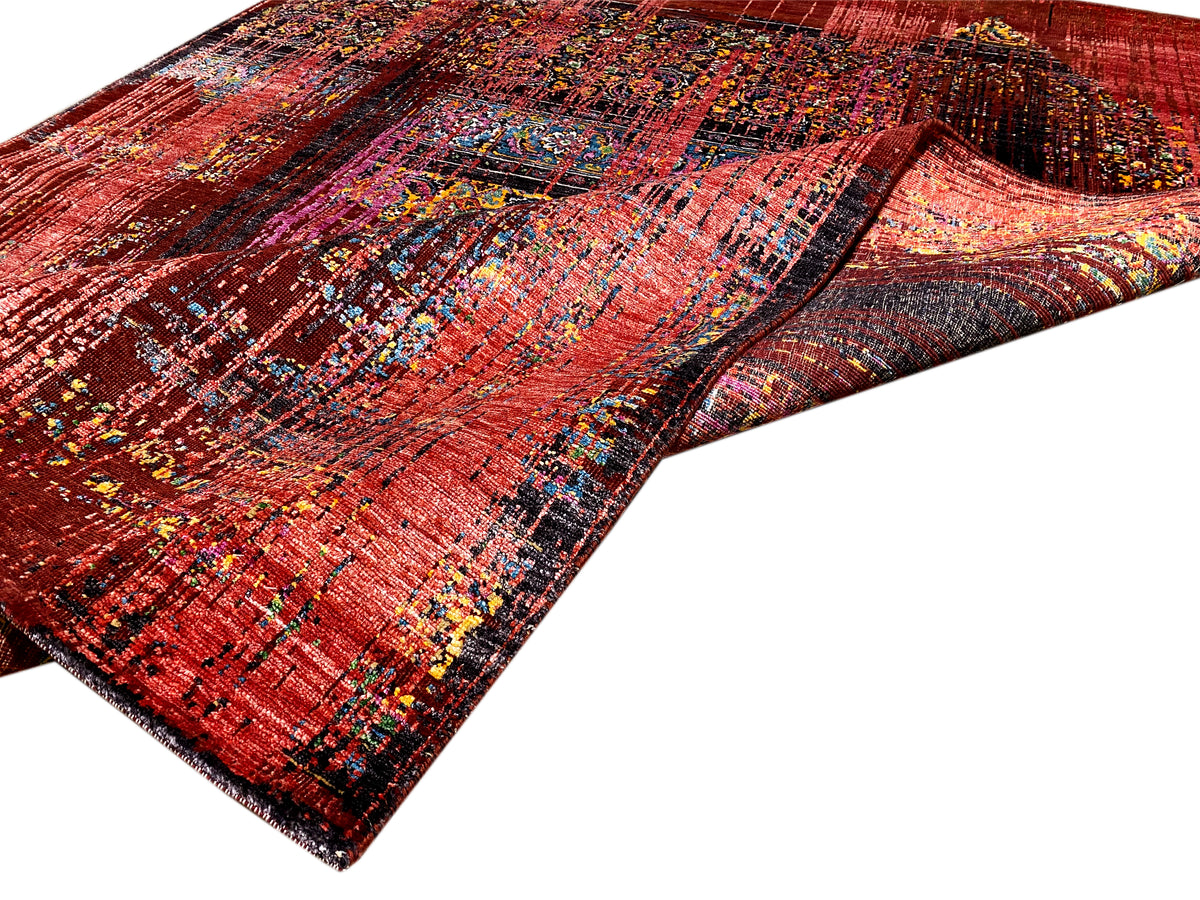 Designer-Teppich, rechteckig, rötliche Musterflächen mit bunten Linien, gefaltete Liegeansicht