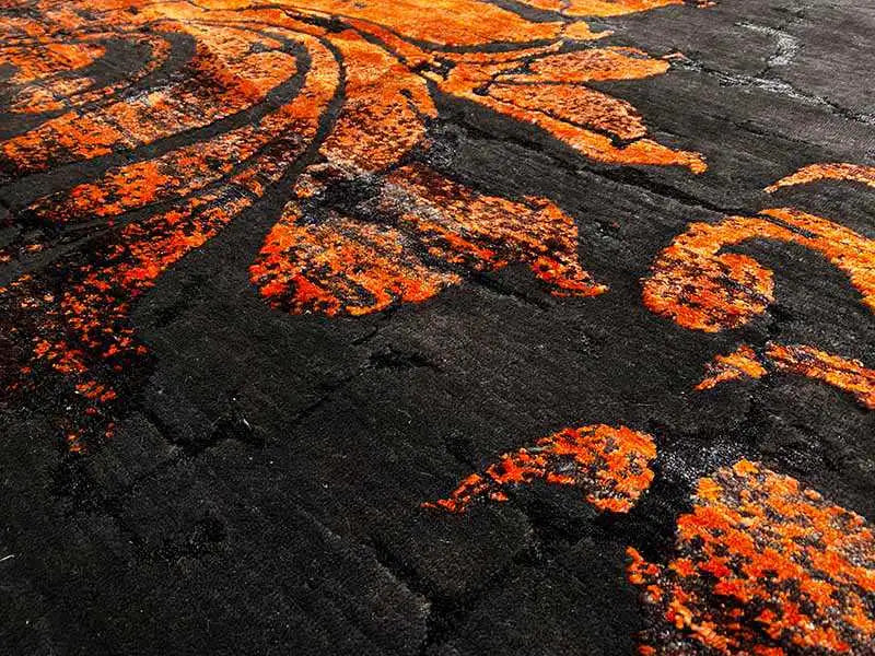 Carpet pattern in detail: anthracite-colored surface with orange floral ornaments.
