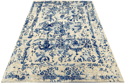 Rectangular rug: white-beige base with a bold blue ornamental and floral pattern