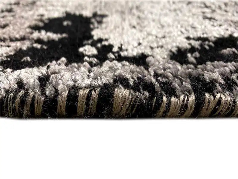 Carpet edge and pile in the close-up: dark and light fibers, gray-black