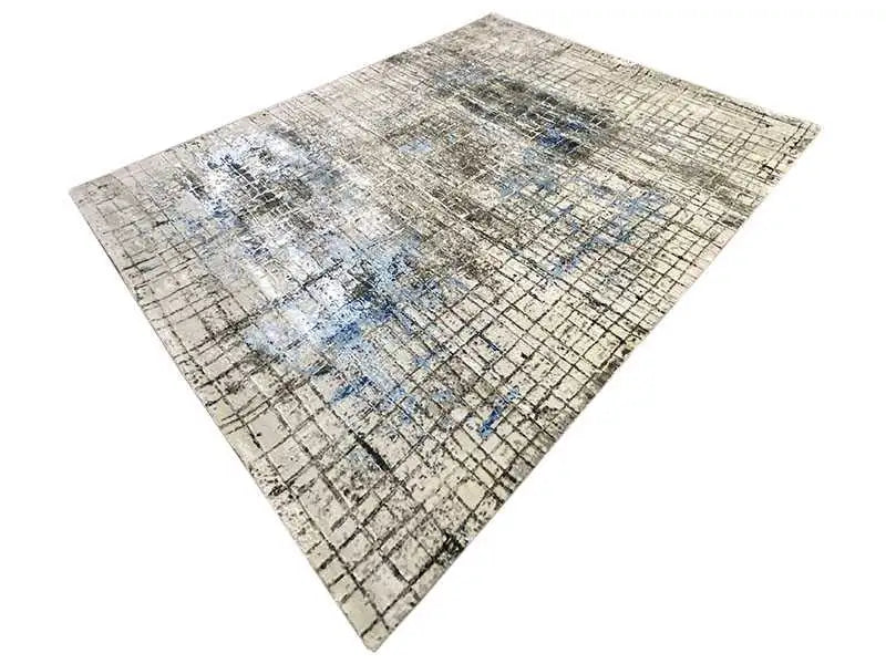 Rug with a vintage grid look, beige-gray and light blue patches of color, photographed at an angle