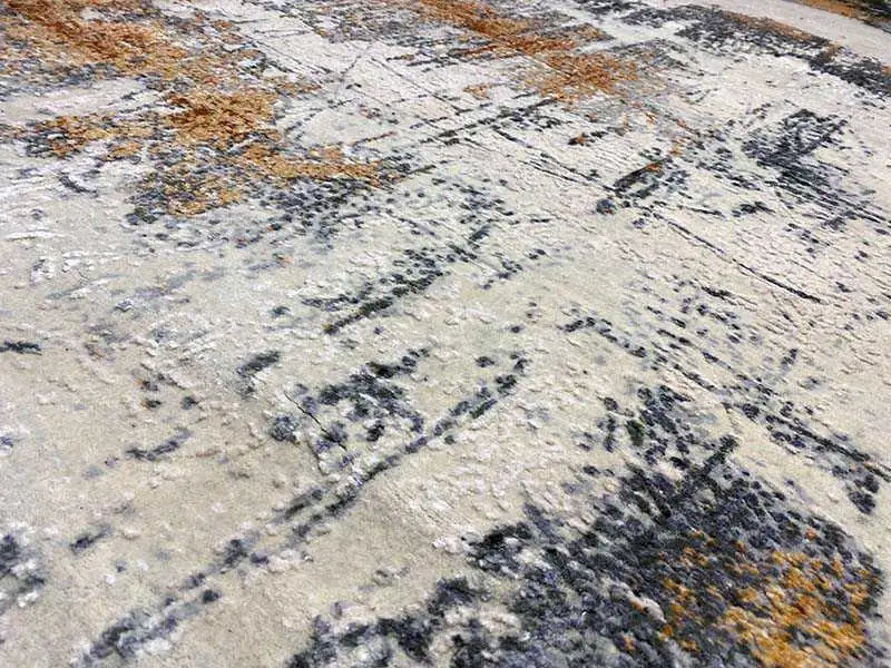 Designer rug, detail view: abstract color blocks in light gray, black, and ochre