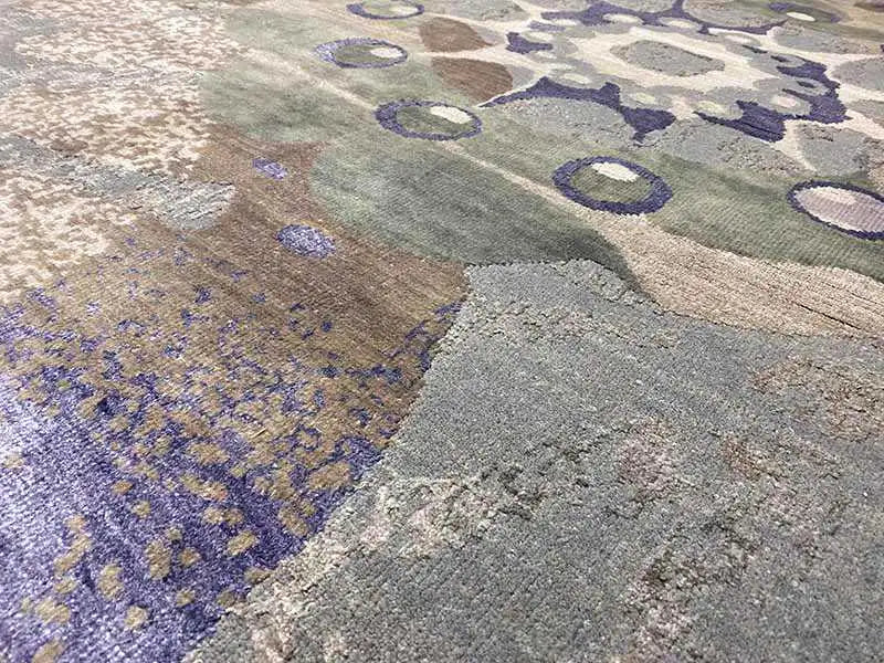 Carpet detail with abstract ovals and areas of color in gray, blue, and violet