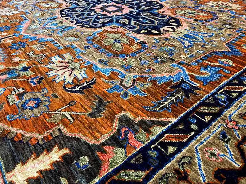 Close-up: colorful ornamental patterns in the carpet, blue, orange, and beige on a dark background