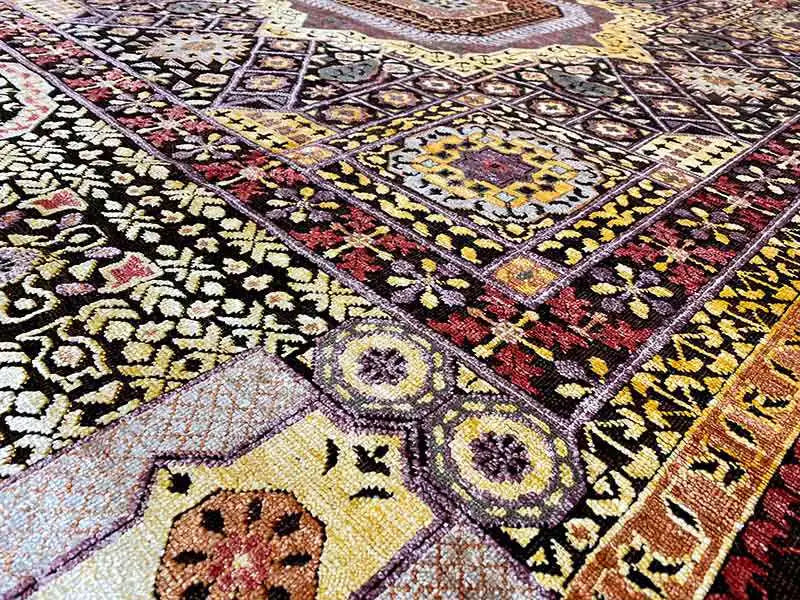 Rug with an intricate ornamental design in black, yellow, red, and cream