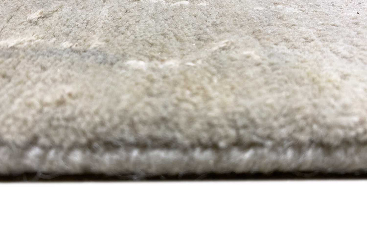 Close-up of a carpet edge with a dense pile texture on a light beige background