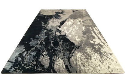 Rectangular rug with an abstract pattern in dark blue, gray, and light beige