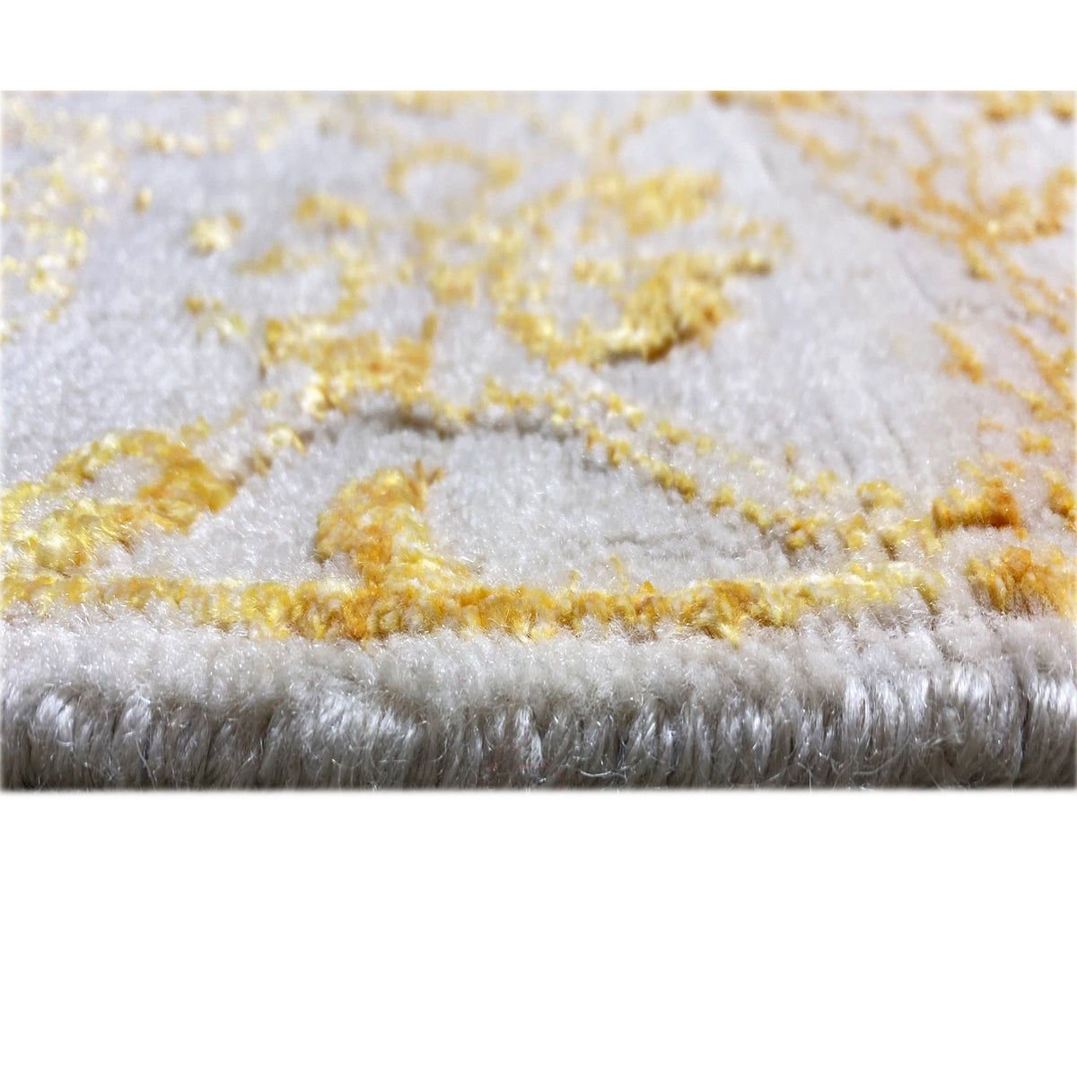 Close-up of designer rug 316x245 cm: pile and bound edge with golden-yellow accents
