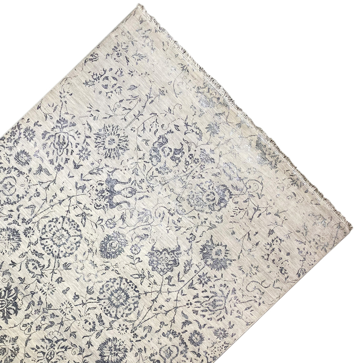 Designer rug corner with a blue pattern and hemmed edge, light base color