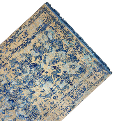 Corner of the rug with a blue ornament, beige background, and hemmed edge