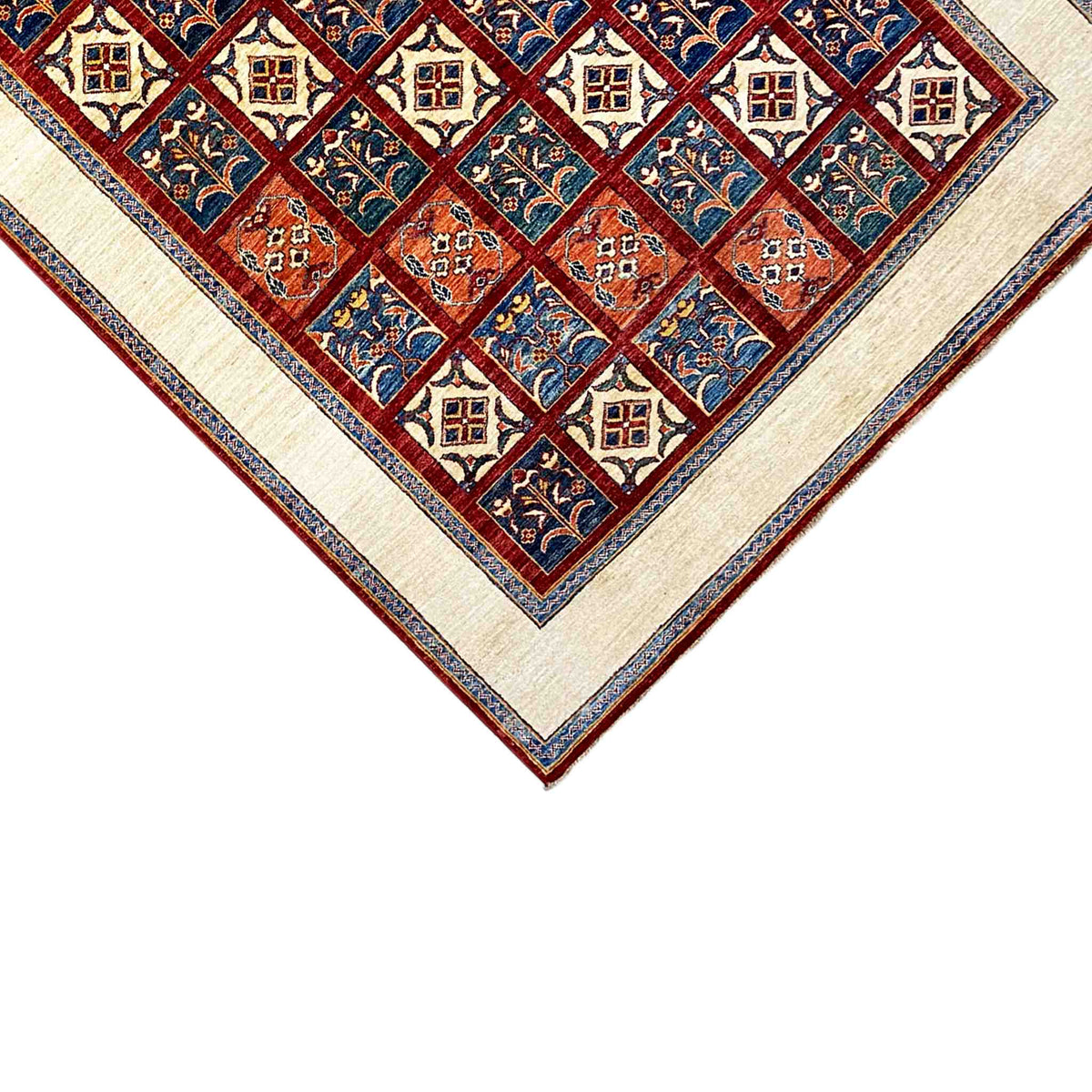 Close-up of the carpet’s center: diamond and tile patterns in blue and red, with a cream-colored border