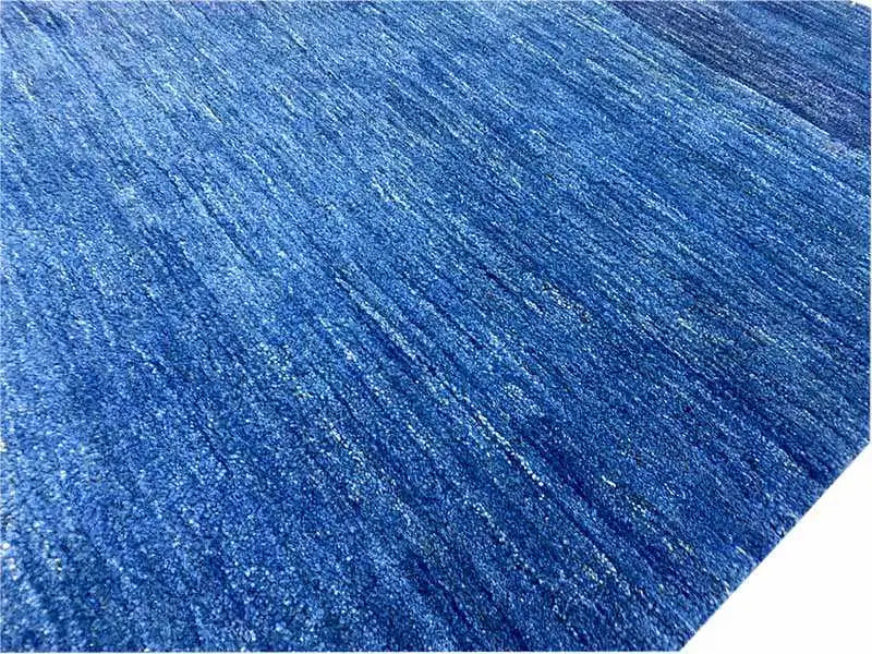 Close-up of the surface: blue Gabbeh rug with a mottled texture.