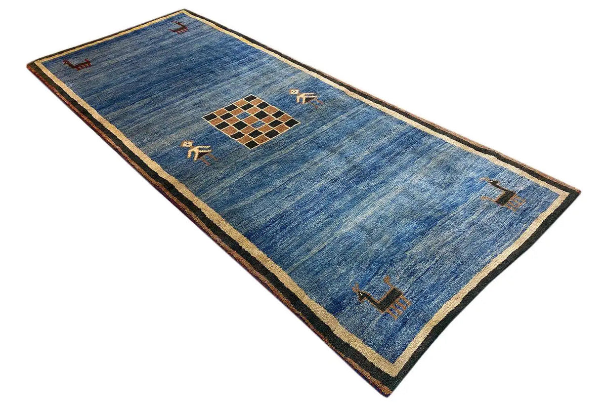 Blue Gabbeh rug with a beige border; rectangular, geometric pattern in the center