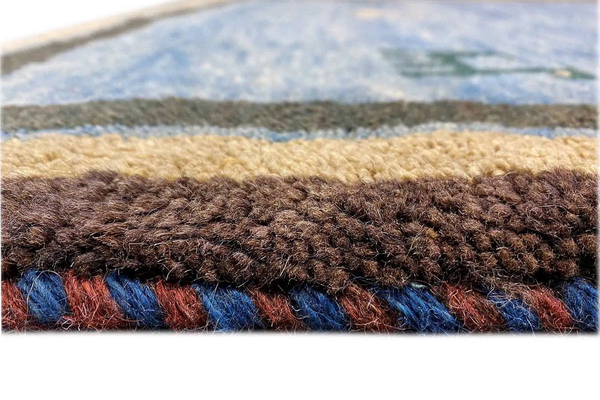 Carpet edge with a dense pile, blue-brown color layering, and beige trim