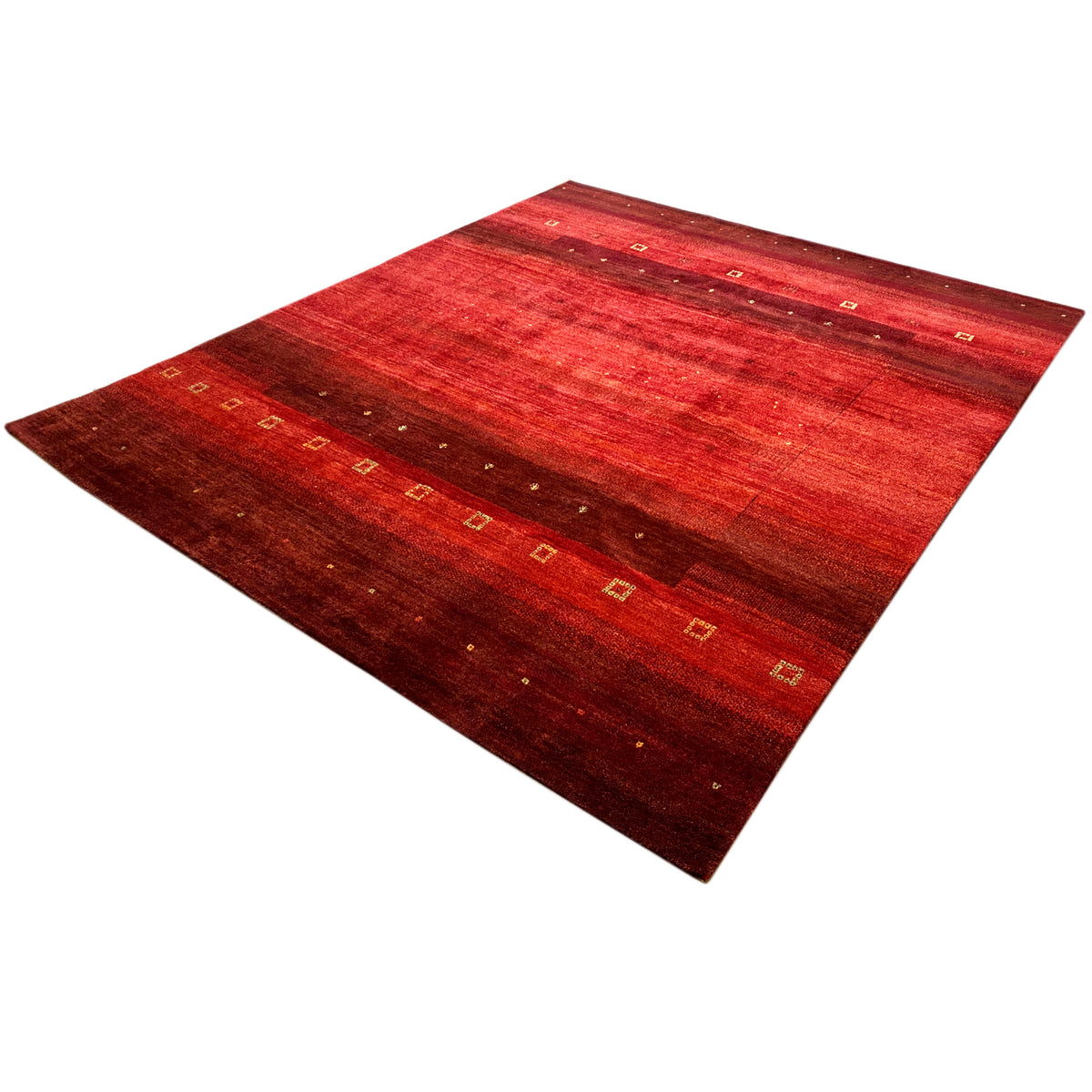 Hand-knotted Gabbeh rug with red gradation, diagonal view, and golden pattern elements