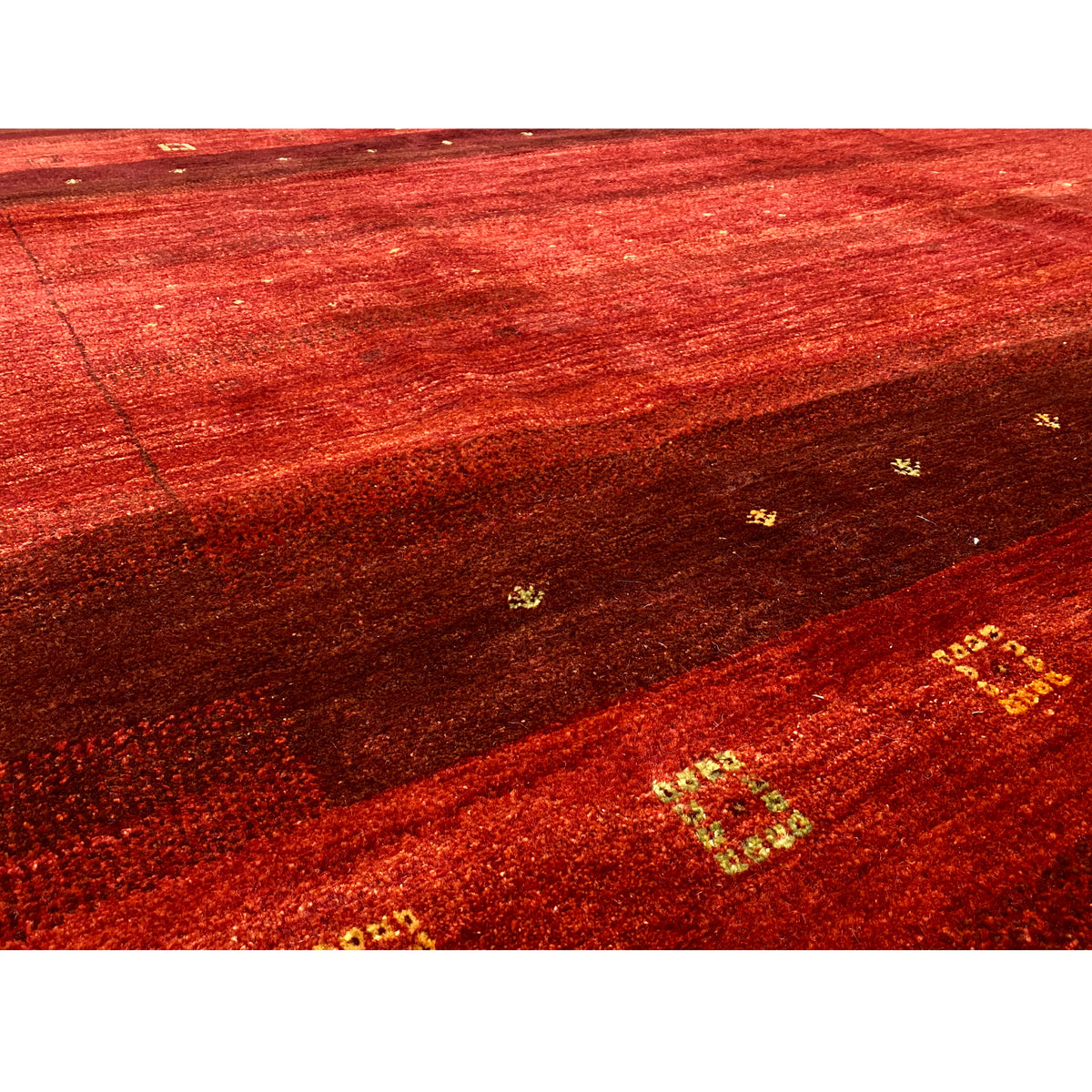 Gabbeh rug close-up: red bands with a dark background and golden patterned dots