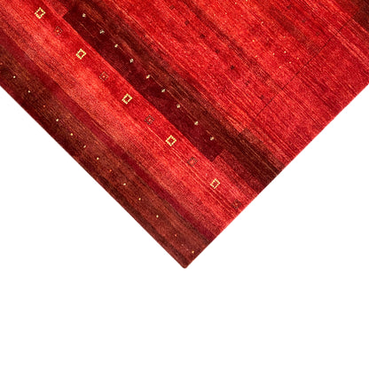 Gabbeh rug close-up of the corner: red pile, golden squares, and fine threads