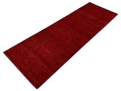 Gabbeh runner rug with a dark red hue and an even woven pattern